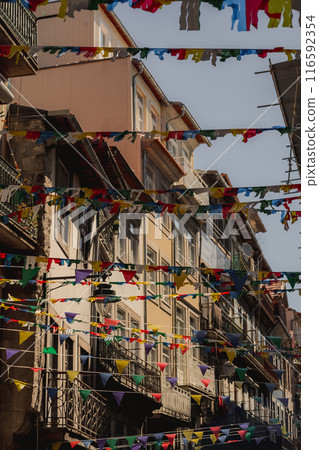 A row of buildings adorned with bright flags creates a colorful display A row of buildings adorned with bright flags creates a colorful display 116592354