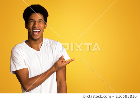 Advertisement concept. Happy guy pointing on empty space, yellow background Advertisement concept. Happy guy pointing on empty space, yellow background 116593816