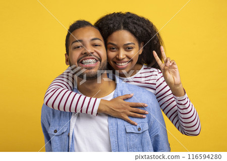 African American man and woman are embracing each other tightly, with big smiles on their faces. They both seem genuinely happy and content in each others arms. 116594280