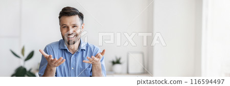 Successful handsome businessman sitting at desk in office, talking at camera, sharing his experience and ideas, free space 116594497