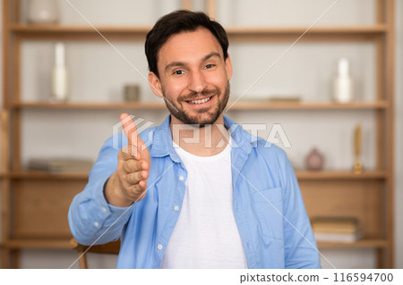 Smiling friendly bearded millennial man manager sitting at desk at modern office, outstretching hand at camera, businessman greeting business partner or employee, job interview 116594700