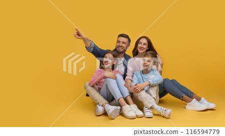 A joyful family is sitting closely with a father pointing at something out of frame, creating a moment of togetherness and curiosity, pointing at copy space on yellow background A joyful family is sitting closely with a father pointing at something out of frame, creating a moment of togetherness and curiosity, pointing at copy space on yellow background 116594779