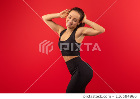 A woman is shown wearing a black sports bra top and leggings. She appears to be engaged in physical activity or exercise, showcasing her athletic attire. A woman is shown wearing a black sports bra top and leggings. She appears to be engaged in physical activity or exercise, showcasing her athletic attire. 116594966