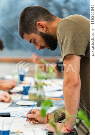 Young man leaning on a table while making a design. Vertical 116595043