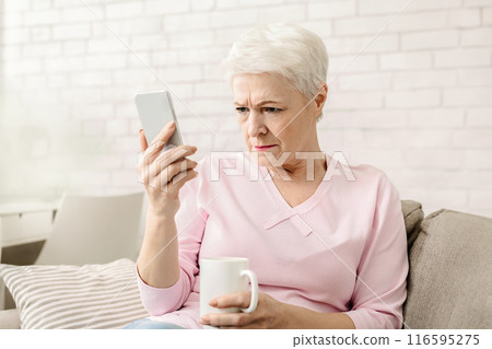 Myopia. Senior woman holding phone near face, trying to see message, free space Myopia. Senior woman holding phone near face, trying to see message, free space 116595275