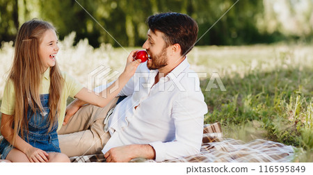 Happy family relaxing in park, eating fruits at picnic and having fun Happy family relaxing in park, eating fruits at picnic and having fun 116595849