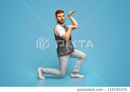 Funny millennial guy dancing in egypt style on blue background, studio, copy space Funny millennial guy dancing in egypt style on blue background, studio, copy space 116595878