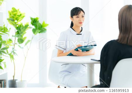 A female medical worker interviewing a patient 116595913