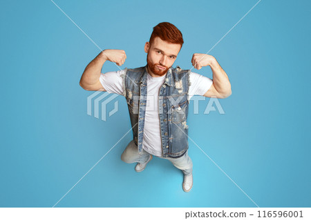 Awesome strong caucasian man showing his power and biceps on blue background 116596001