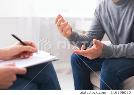 Psychotherapist writing notes, assessing patient's health and giving diagnosis to man sitting on couch during counseling session , panorama, free space 116596050