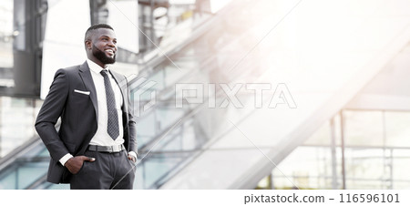 Successful Business. Confident African Businessman Standing Holding Hands In Pockets In Urban Area Outside. Free Space Successful Business. Confident African Businessman Standing Holding Hands In Pockets In Urban Area Outside. Free Space 116596101