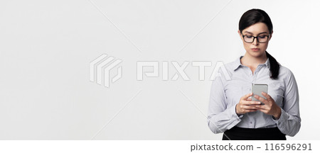 Business Chat. Serious Businesswoman Using Cellphone Texting Standing On White Background. Studio Shot, Empty Space 116596291