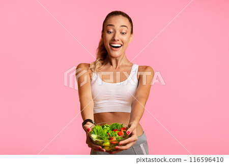 Excited Slim Woman Holding Vegetable Salad In Bowl Standing On Yellow Studio Background. Free Space 116596410