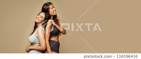Laughing young arabic and middle eastern women in different underwear, enjoy free time, natural beauty care, isolated on beige background, studio. Fun, lifestyle, health care and fashion, copy space 116596416