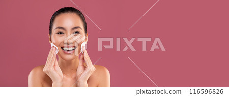 Closeup photo of happy topless young korean woman cleansing her skin with cotton pads and smiling over purple studio background, removing makeup with beauty product, copy space Closeup photo of happy topless young korean woman cleansing her skin with cotton pads and smiling over purple studio background, removing makeup with beauty product, copy space 116596826