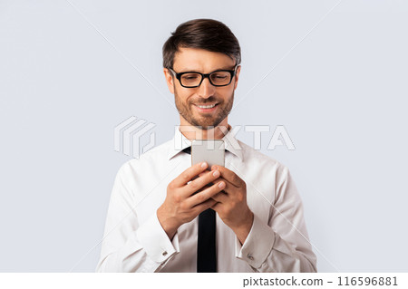 Positive Businessman Texting On Mobile Phone Standing Over White Background. Studio Shot, Free Space 116596881