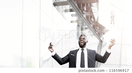 Business Success Concept. Excited Businessman Shouting In Joy Throwing Papers Celebrating Promotion At Work Standing Outdoors In City. Business Success Concept. Excited Businessman Shouting In Joy Throwing Papers Celebrating Promotion At Work Standing Outdoors In City. 116596917
