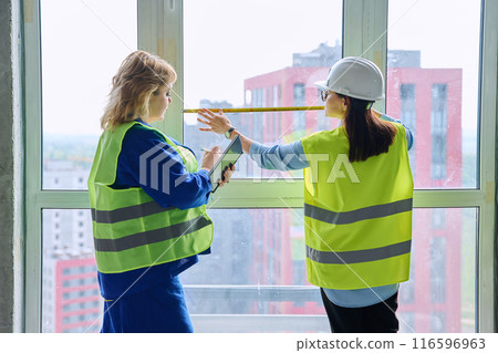 Two female industrial workers taking measurements of windows for decoration 116596963