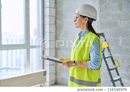 Technical profession woman in protective vest helmet working on construction Technical profession woman in protective vest helmet working on construction 116596976