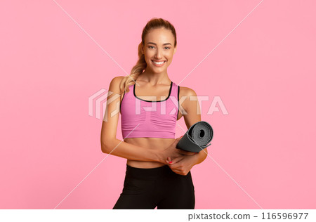 Smiling Girl Holding Fitness Mat Looking At Camera Standing Over Yellow Background. Studio Shot 116596977