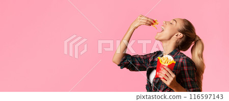 Hungry Young Woman Eating French-Fries On Yellow Studio Background. Cheat Meal Concept Hungry Young Woman Eating French-Fries On Yellow Studio Background. Cheat Meal Concept 116597143