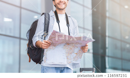 Tourism concept. Man standing near airport building and searching map, panorama with empty space Tourism concept. Man standing near airport building and searching map, panorama with empty space 116597231