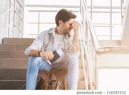 Travel Restrictions. Depressed Man Sitting On Stairs In Airport With Passport And Tickets, His Flight Cancelled Due To Coronavirus Outbreak 116597232