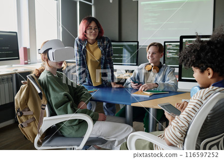 Group of ethnically diverse teenagers using VR headset and digital tablet during modern Computer Science class 116597252