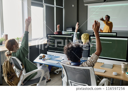 Group of multi-ethnic students raising hands to answer teachers question in Computer Science class, copy space Group of multi-ethnic students raising hands to answer teachers question in Computer Science class, copy space 116597256