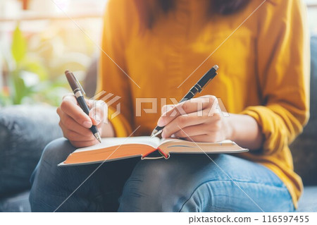 Young woman cozy sweater writing in journal candlelight softly lit cafe 116597455