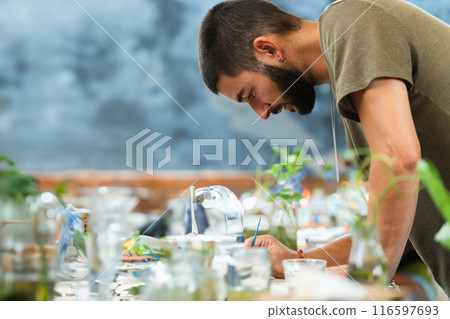 Creative director designing on a table full of colors and a blue wall behind with copy space Creative director designing on a table full of colors and a blue wall behind with copy space 116597693