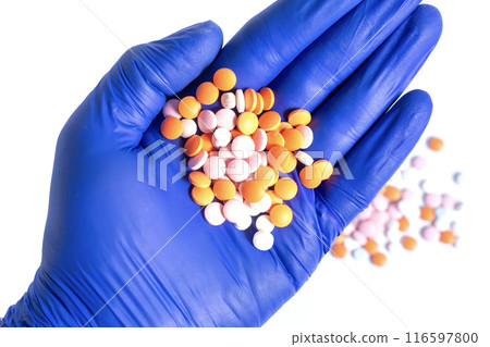 Hand in blue glove holding a pile of multicolor pills isolated on white background. closeup 116597800