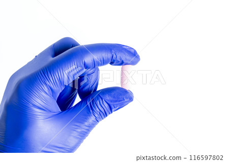 Doctor's hand in blue glove holding a pink pill isolated on white background 116597802