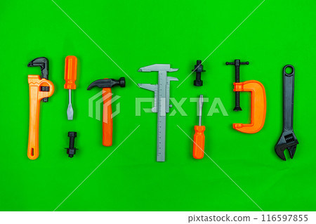 Set of toy working tools on colorful green paper background. Industrial background concept Set of toy working tools on colorful green paper background. Industrial background concept 116597855