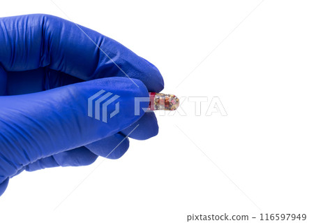 Hand in blue glove holding a medicine capsule isolated on white background. Hand in blue glove holding a medicine capsule isolated on white background. 116597949