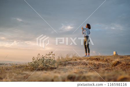 A woman peacefully enjoying the sunset in nature, capturing a beautiful moment outdoors 116598116
