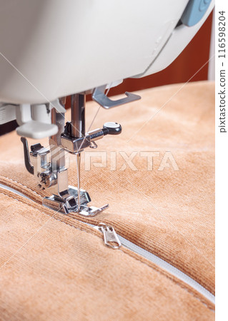 Modern sewing machine special presser foot with beige velveteen fabric and zipper, closeup 116598204