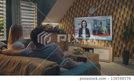 Couple watches breaking news on big TV display and discusses US presidential elections 116598576