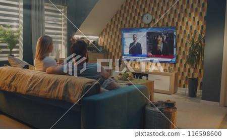 Caucasian couple watches news broadcast about United States Election Day on TV 116598600