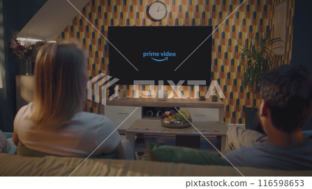 Caucasian couple starts to watch movie on Prime Video on TV resting at home 116598653