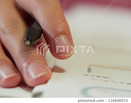 A close-up of a sixth-grade elementary school student solving exam questions 116600053