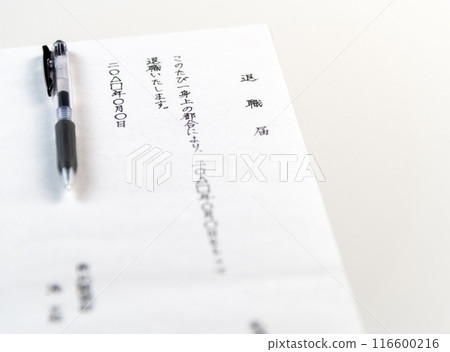 A handwritten resignation letter and a black gel ink pen on a white table 116600216