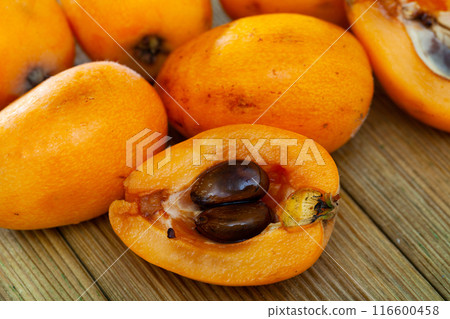 Whole and half fresh yellow loquat on wooden table 116600458