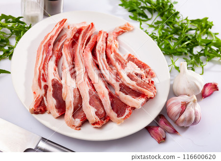 Raw mutton chops on plate with herbs and spices 116600620