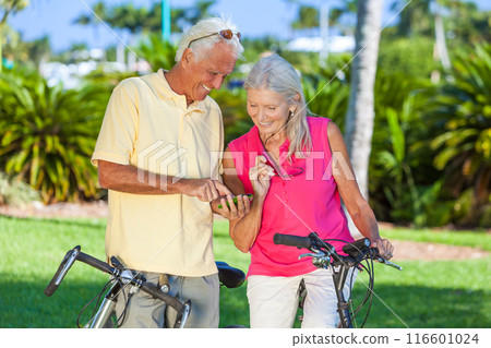 Happy Senior Couple on Bicycles In a Park Using a Smartphone Happy Senior Couple on Bicycles In a Park Using a Smartphone 116601024