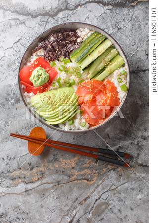 Sushi Bowl with salmon, avocado, cucumber, white rice, sesame, ginger and wasabi closeup. Vertical top view 116601101