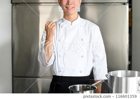 一位年輕男廚師在廚房裡做拳頭泵 116601359