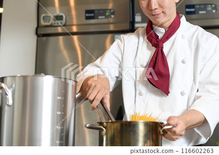Asian male chef boiling pasta in the kitchen Asian male chef boiling pasta in the kitchen 116602263