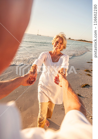 Happy Senior Old Retired Couple Walking Holding Hands on Beach at Sunset Happy Senior Old Retired Couple Walking Holding Hands on Beach at Sunset 116602280
