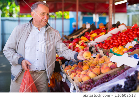 Man choosing peaches in market Man choosing peaches in market 116602518